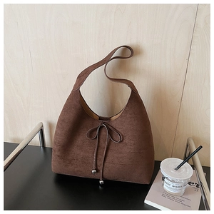 Detailed view of dark brown suede hobo bag with slender bow and silver metal beads