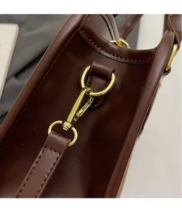 Detail of dark brown leather handbag featuring high-quality gold metal hook and fine stitching