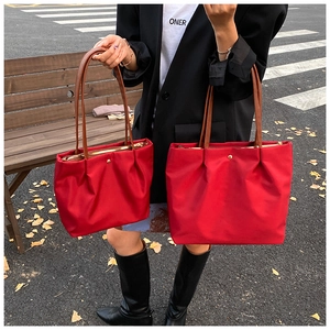 Detail of red nylon tote bags in medium and large sizes with premium leather handles
