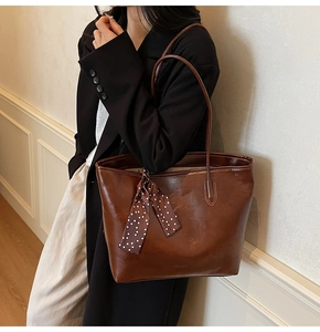 Detail of dark brown wax leather tote bag with a polka dot scarf on a model's shoulder