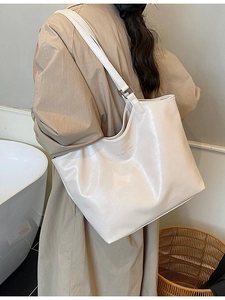 Minimalist beige oversized tote bag in pebbled faux leather worn by a model in a trench coat