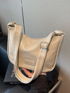 Minimalist cream white dumpling bag with adjustable shoulder strap and metal logo