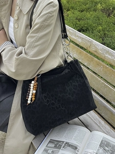 Black leopard jacquard tote bag with chain strap and wooden bead charm on a model