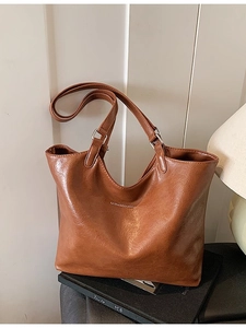 Vintage brown large-capacity tote bag with long straps on a minimalist display stand