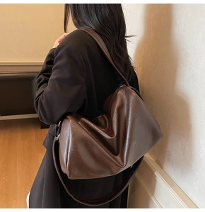 Detail view of a large dark brown slouchy tote bag made of high-gloss soft leather