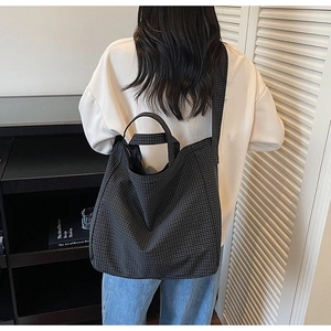 Detailed back view of a black and white grid canvas tote bag with adjustable shoulder straps