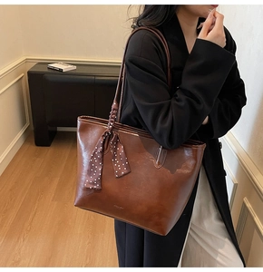 Detail of dark brown tote bag featuring a leather texture and a polka dot silk scarf handle