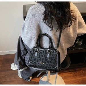 Detail of leopard print patchwork Boston bag worn by model in a cozy home setting