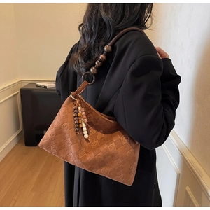 Detail of vintage brown suede hobo bag with quilted texture and wooden bead strap