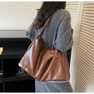 Detail view of caramel brown faux leather tote bag showing soft texture and drape