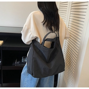 Detail of a large checkered canvas tote bag with dual handles and long shoulder strap
