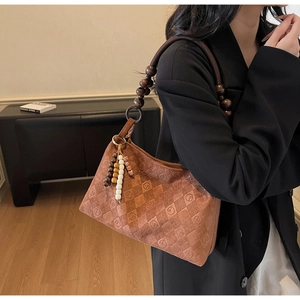 Detail of vintage brown suede shoulder bag with unique wooden bead handle and tassel