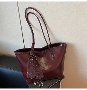 Detail of burgundy leather tote bag with a decorative brown polka dot silk scarf handle
