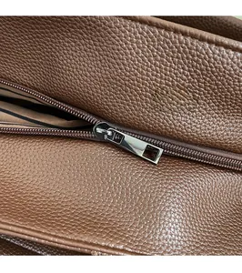 Dettaglio macro della zip argento e pelle marrone grana litchi sulla borsa a spalla