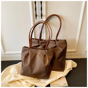 Detail of two coffee brown nylon tote bags in different sizes with elegant leather straps