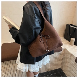 Detail of dark brown suede hobo bag with drawstring bow and metallic spherical charms