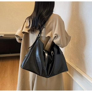 Detail of the large black glossy leather tote bag showing a supple slouchy silhouette