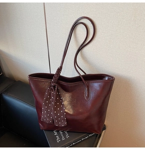 Detail of wine red leather tote bag with elegant polka dot silk scarf on handle