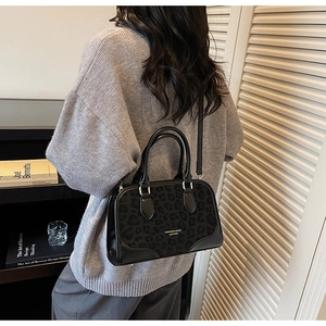 Detail of black faux suede leopard print handbag with sturdy top handles and shoulder strap