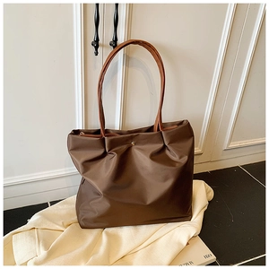 Detail of dark brown nylon tote bag with pleated closure and golden snap fastener