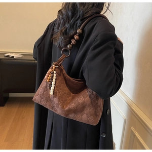 Detail of vintage brown suede shoulder bag featuring diamond quilting and wooden bead strap