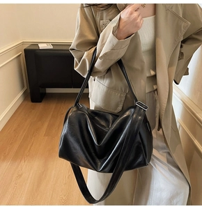 Model wearing a large black soft leather tote bag with a natural drape for daily commute