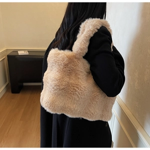 Détail du sac cabas en peluche beige montrant la texture douce sur un mannequin en manteau