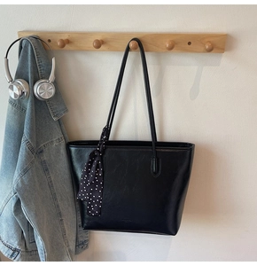 Detail of black pebbled leather tote bag with elegant polka dot scarf accessory