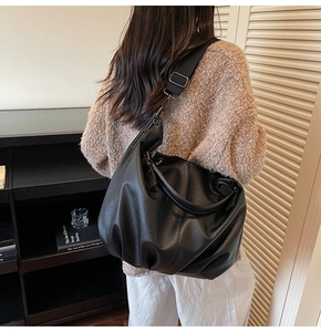 Détail d'un sac cabas noir en cuir à texture litchi avec deux types de bandoulières chic