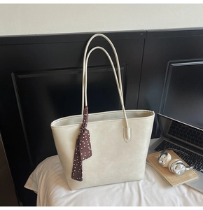 Close-up of cream tote bag featuring a polka dot scarf handle and a minimalist design