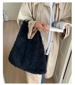 Detail of a large black plush tote bag showing fluffy faux fur texture and shoulder strap