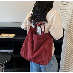 Deep red checkered canvas tote bag shown on model highlighting its large size and soft texture
