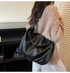 Gros plan du cabas en cuir grainé noir avec détails plissés porté par un mannequin