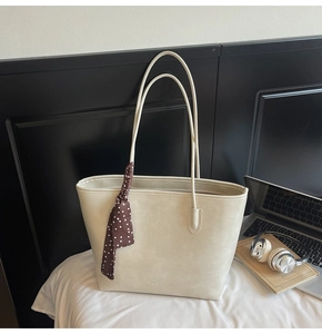 Close-up of cream faux leather tote bag with elegant polka dot scarf accessory