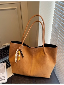 Brown minimalist suede tote bag with colorful bead tassel on office desk with laptop