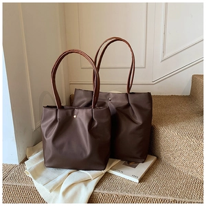 Detail showing two sizes of brown nylon tote bags with sleek metallic buckle accents