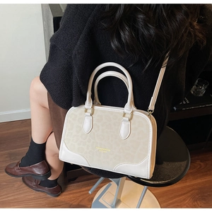 Detail of cream crossbody bag with leopard print texture and gold hardware on model