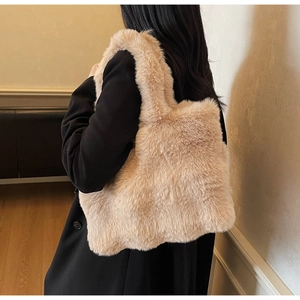 Détail d'un sac cabas en peluche beige porté sur un blazer noir pour le style d'automne