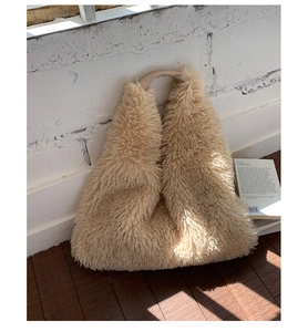 Close-up of a plush beige faux fur hobo bag with smooth handles in a cozy home setting