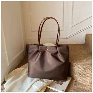 Top view of a large brown tote bag on stairs with magazines and fashion accessories