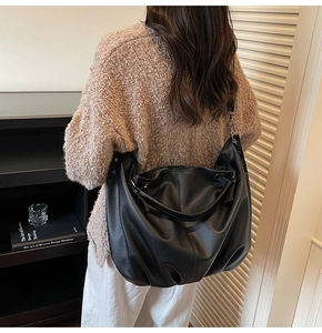 Gros plan du sac hobo noir avec texture en cuir grainé et détails métalliques argentés