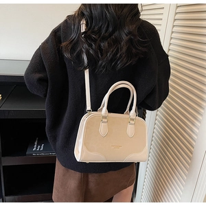 Close-up of beige crossbody bag with adjustable strap shown on model's shoulder