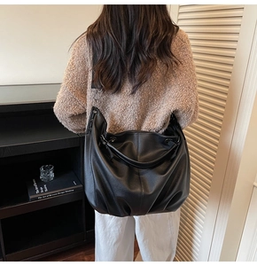Détail du sac cabas en cuir grainé noir avec une large bandoulière réglable