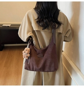 Detail of dark brown suede tote bag with BANATU leather logo and plush bear charm