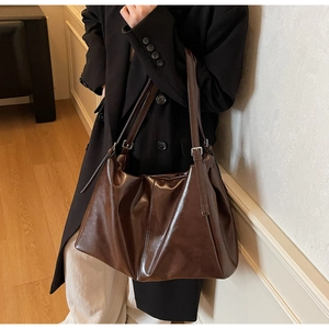 Detailed view of adjustable metal buckle on vintage dark brown leather shoulder bag