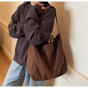 Macro detail of the large brown checkered canvas tote bag showing texture and strap
