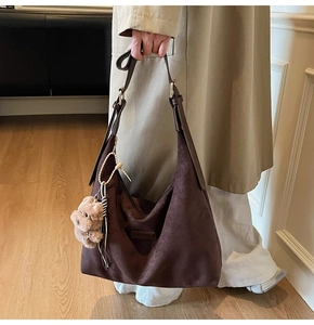 Detail of dark brown suede hobo bag with adjustable strap and cute bear charm