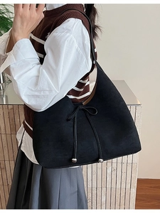 Large black suede hobo bag with drawstring bow detail worn by model for casual style