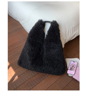 Detailed view of black plush tote bag texture with elegant leather strap and soft fabric