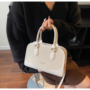 Detail of cream crossbody bag featuring leopard print panel and gold hardware accents